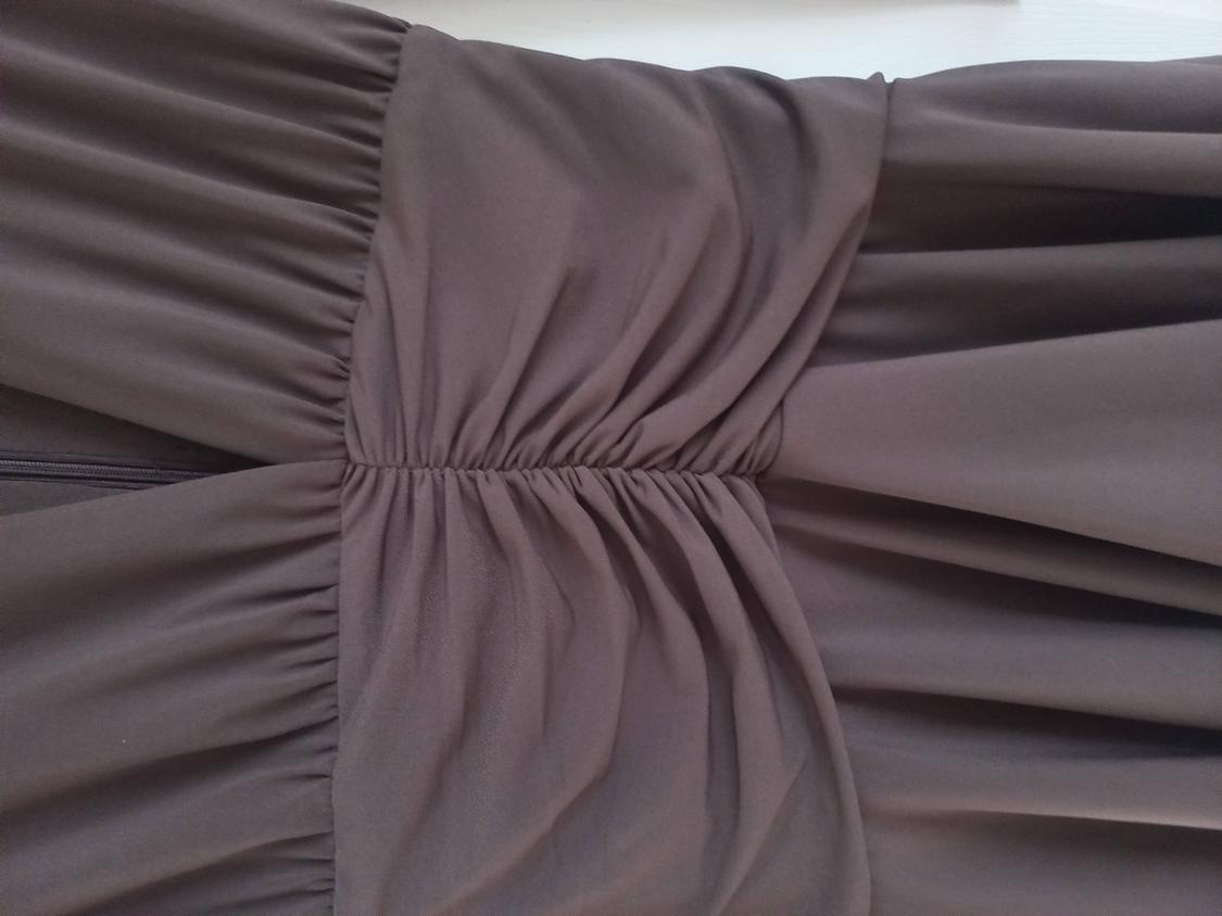 Close-up of a brown garment with gathered detailing in the centre, highlighting the fabric’s soft folds.