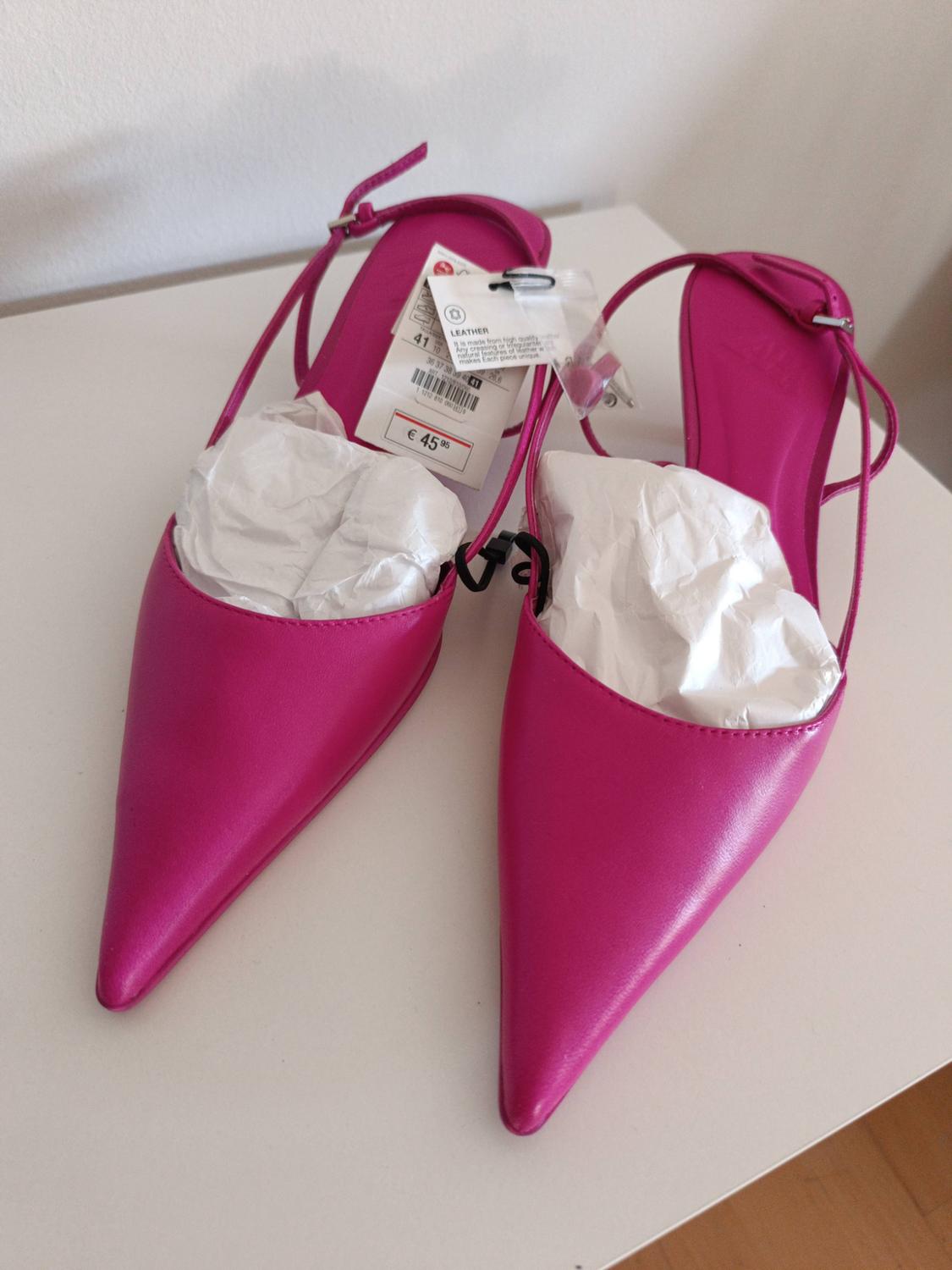 Fuchsia pointed-toe slingback shoes on a white table. They have stuffing paper and labels with the text: 41, LEATHER, € 45.95.