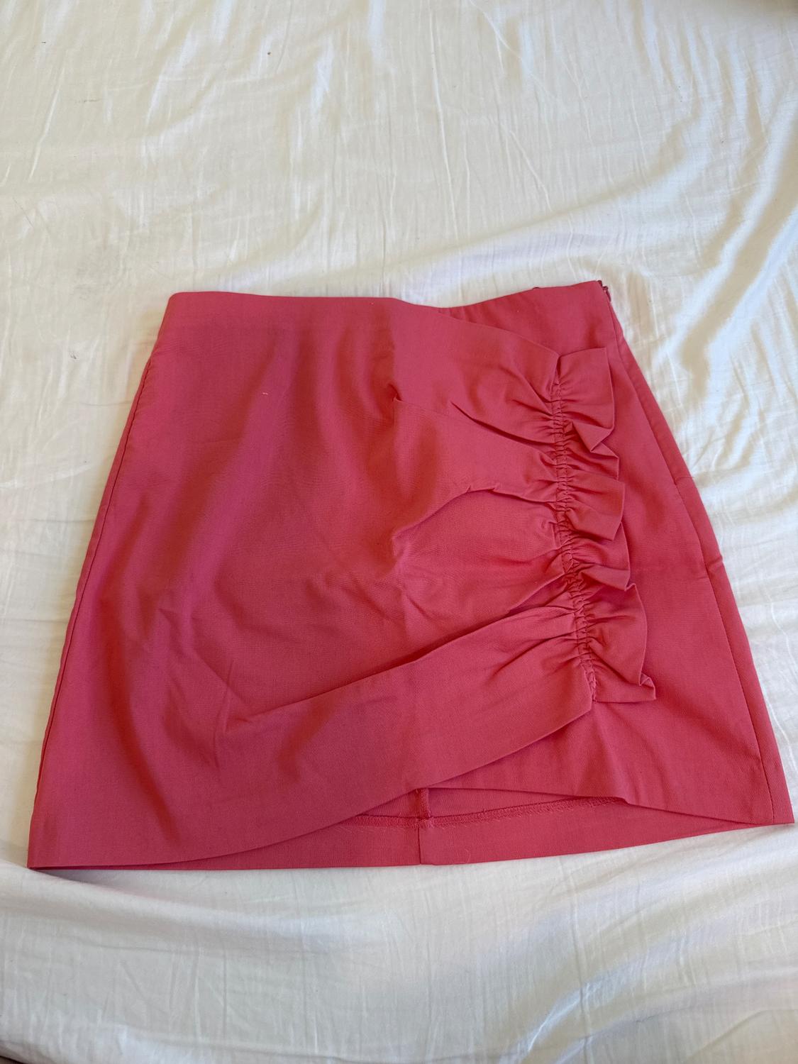 Red mini skirt with ruched detail on the side, on a white surface.