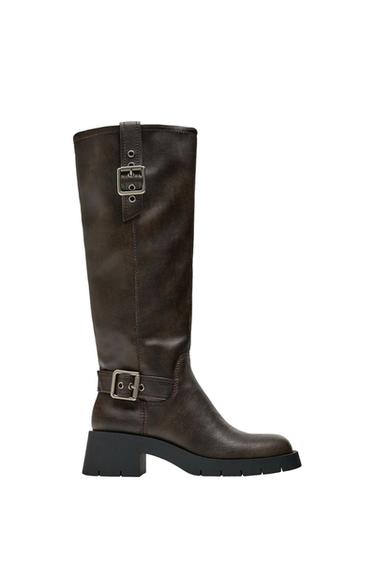 Brown leather tall boot with metal buckles and thick black sole, side view on white background.