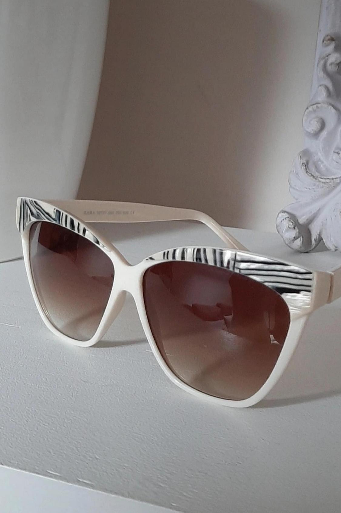 Close-up of white sunglasses with black detailing and dark lenses.