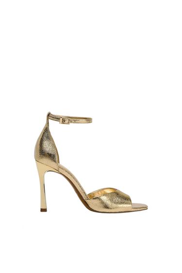 Gold high-heeled sandal with adjustable ankle strap, on a white background.