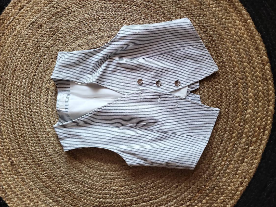 Fine black and white striped waistcoat with buttons, on a braided jute rug.