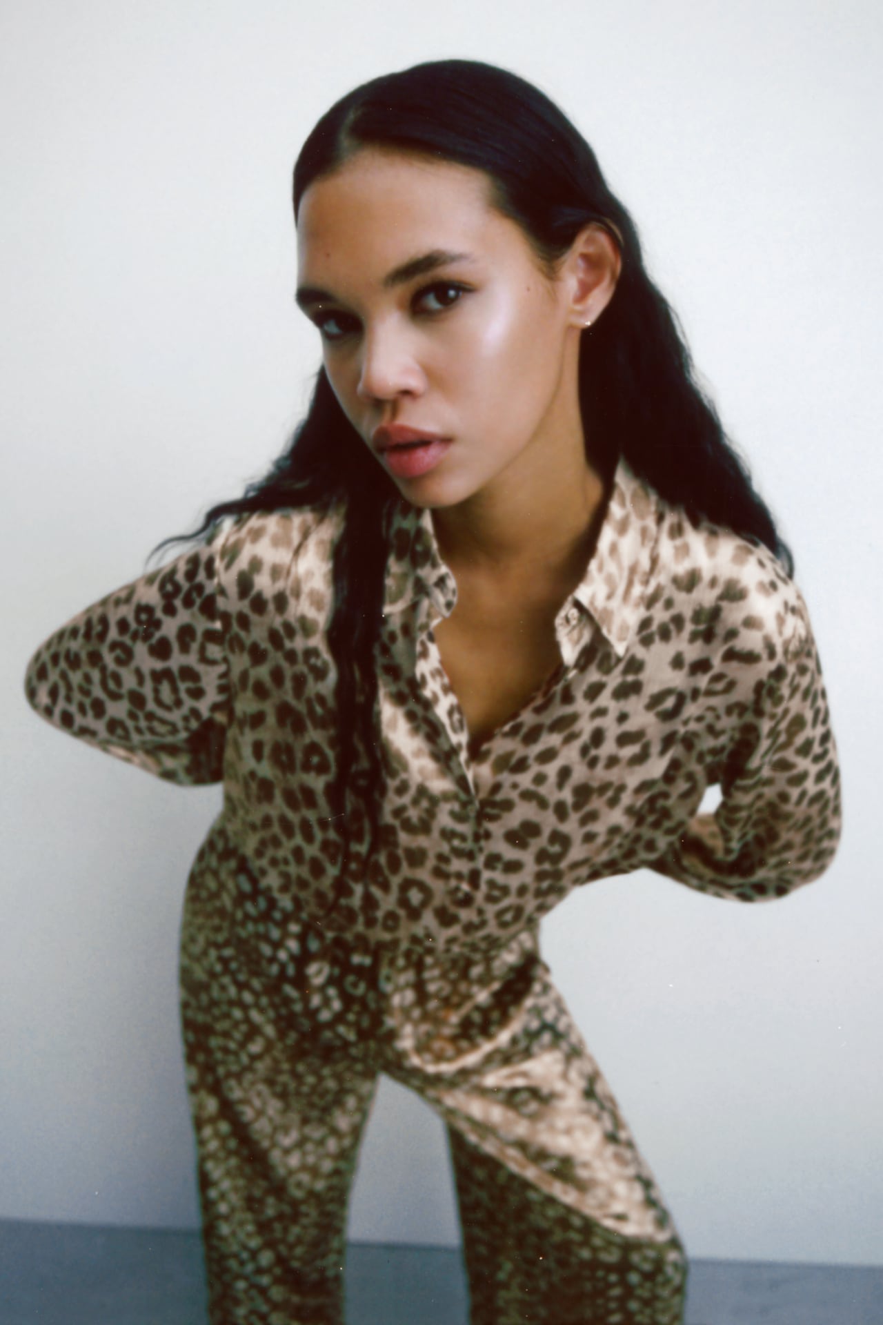 Blurred image of a woman with long dark hair wearing a beige ANIMAL leopard PRINT OVERSIZE SHIRT from Zara with matching trousers and looking into the camera