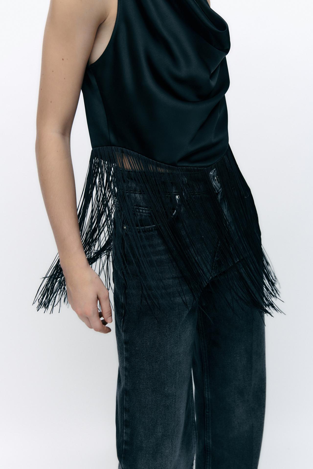 Black satin sleeveless cowl neck top with long fringing at the hem.