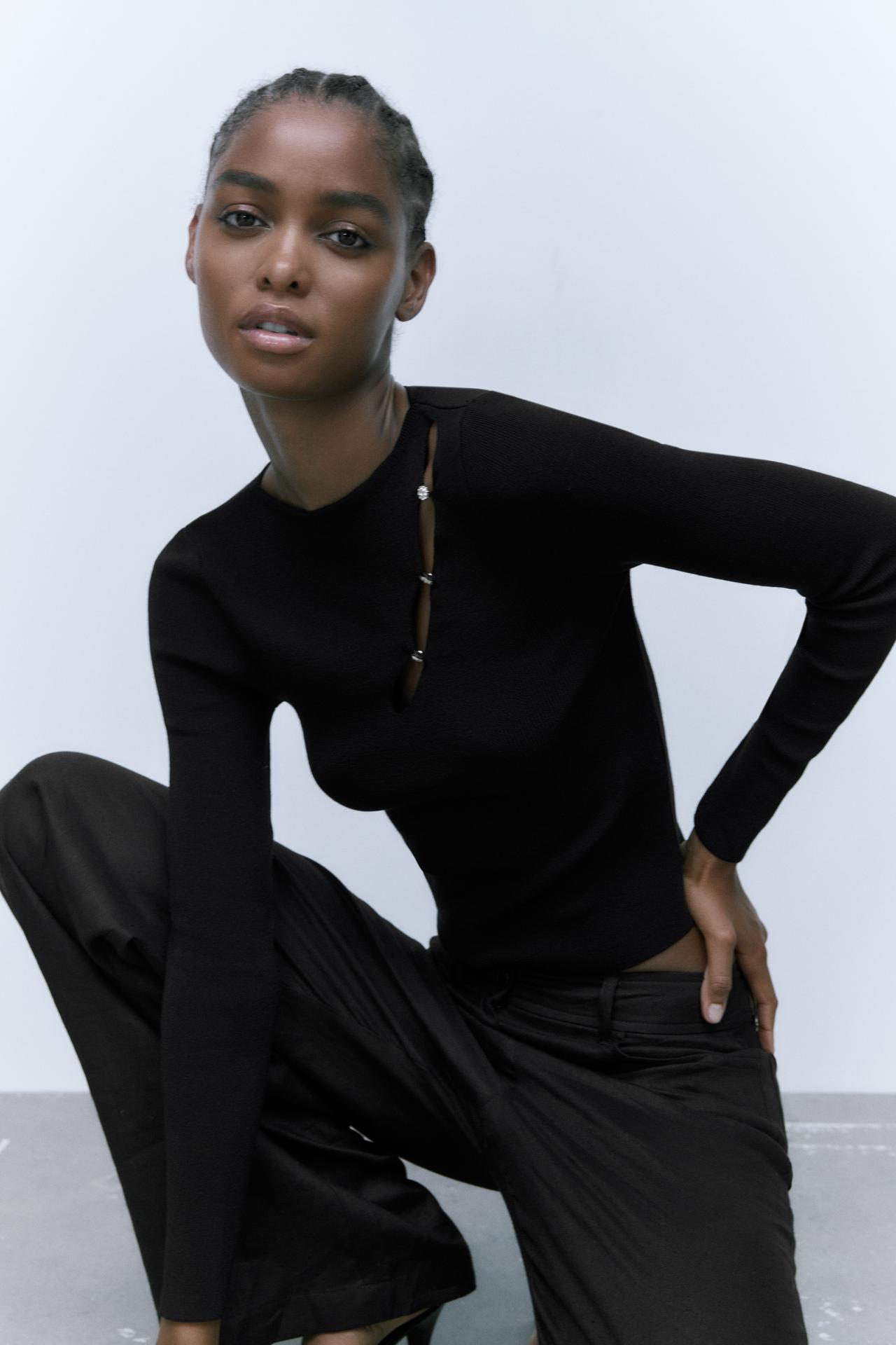 Zara black knit sweater with a round neck and long sleeves. It is lightly cropped, figure-hugging and has a subtle keyhole opening details on one shoulder, with rhinestone buttons.