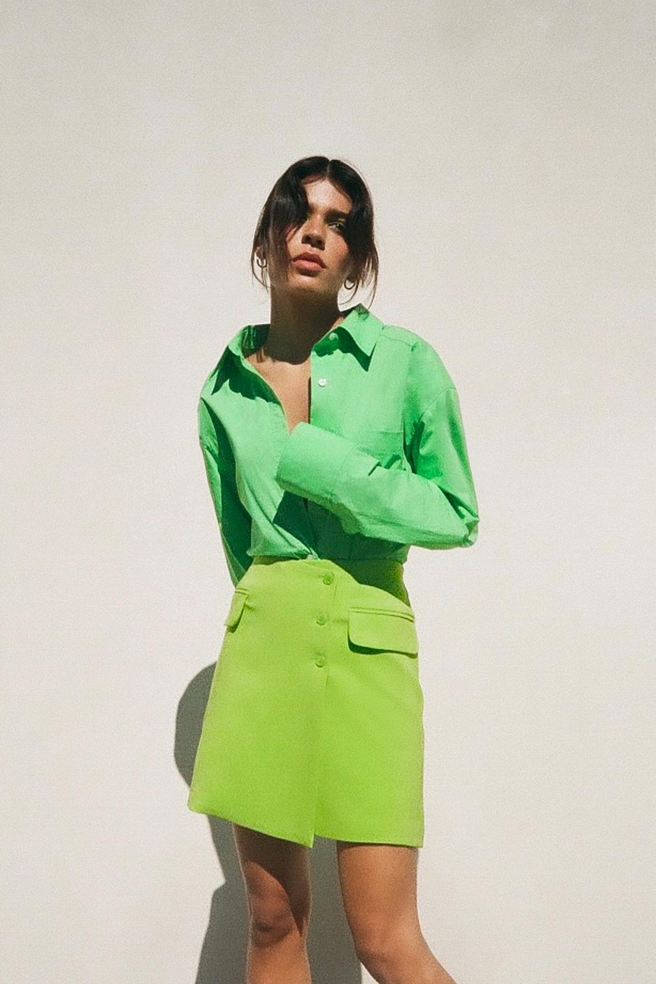 Lime Green High-waist mini skirt. Front flap pockets. Asymmetric Button-down front with 3 buttons.