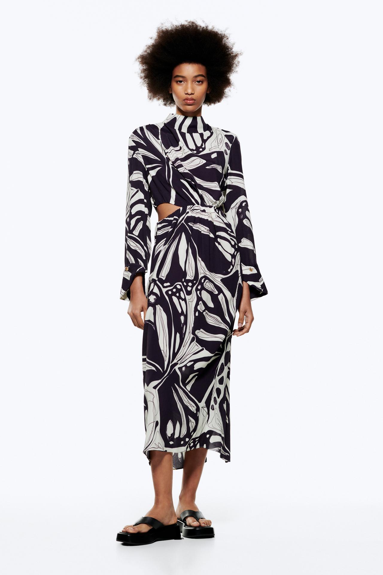 High neck dress in. black and white floral print featuring high neck, long sleeves with cuffs and a button, side slits and invisible zip fastening.