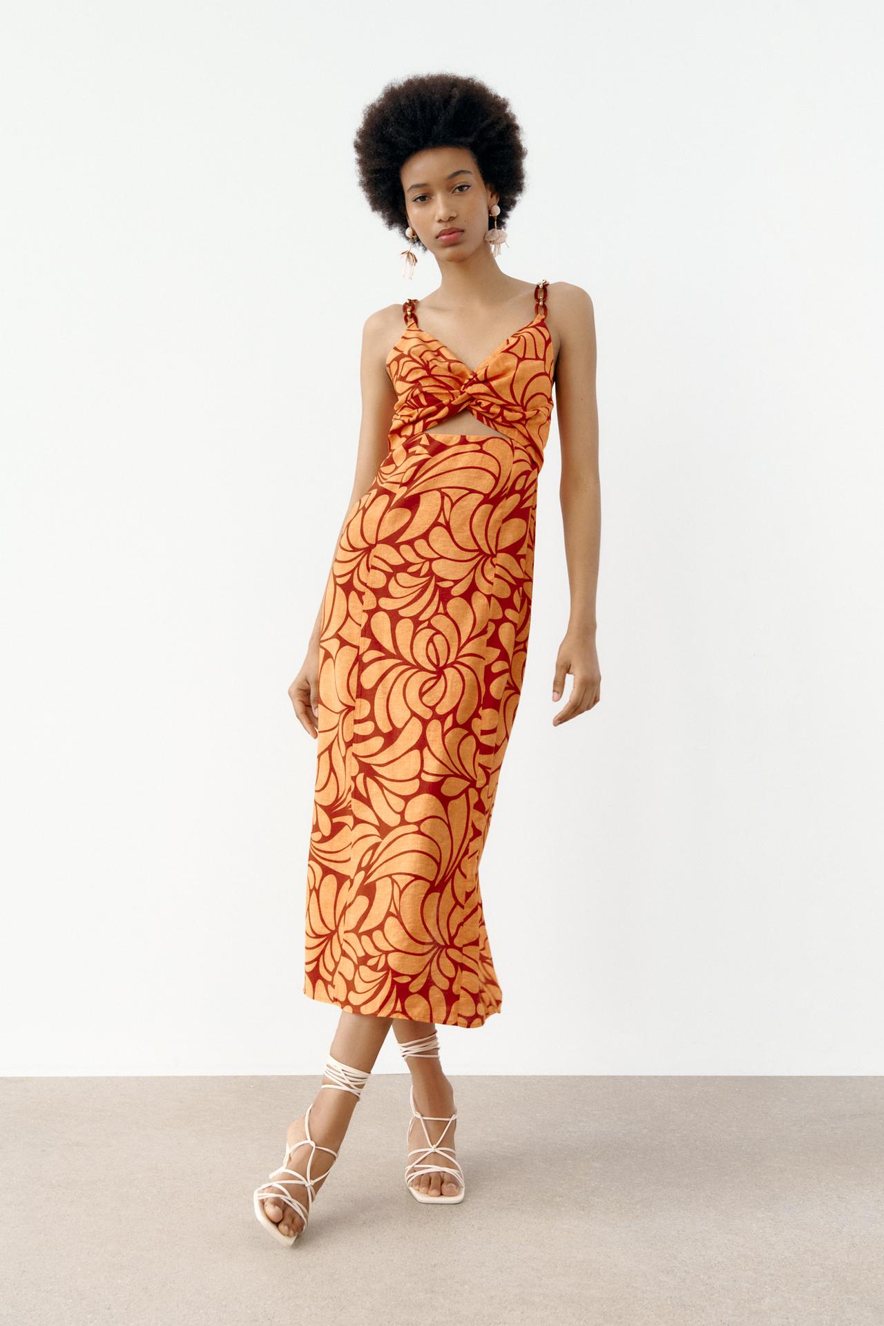 red and orange v-neck midi dress with knot and front slit at the waist. Thin straps with chain appliqué. Back vent. Invisible back zip fastening.