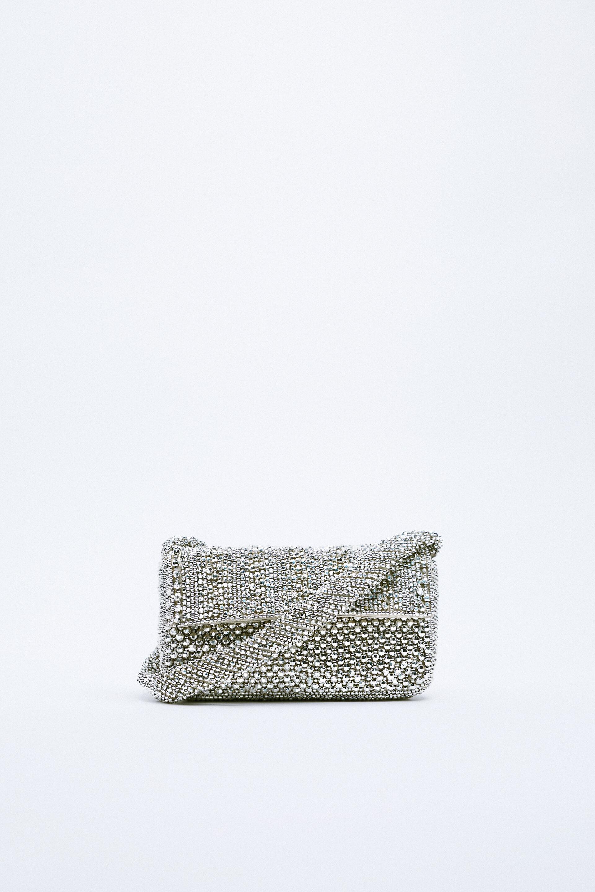 Zara silver shoulder bag with metallic-effect small beads on the exterior. Lined interior with pocket. Shoulder strap. Flap with magnetic clasp closure.
Height x Length x Width 10 x 19,5 x 4 cm. / 3.9 x